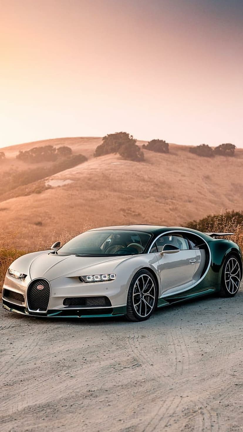 Bugatti Chiron in champagne and green parked on a dirt road during golden hour with a hilly horizon background.