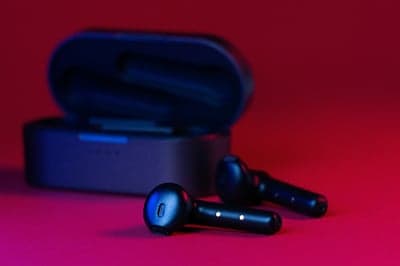 Black Wireless Earbuds and Charging Case on Red Background
