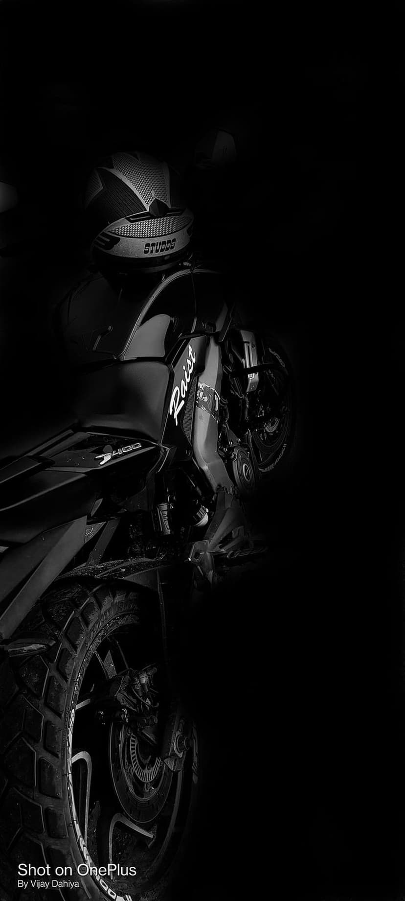 Motorcycle helmet rests on a bike frame with dramatic shadows and highlights in a black and white photograph.