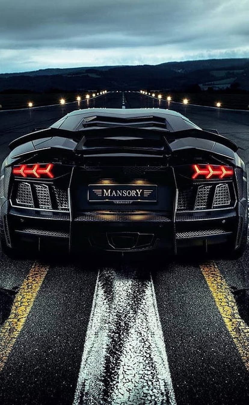 Mansory Aventador supercar with red glowing taillights parked on a dark airfield runway lined with ground lights.