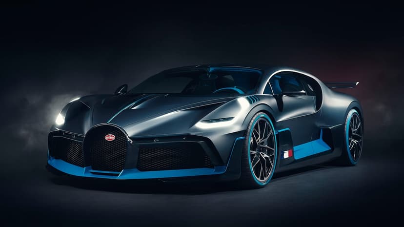 Bugatti Divo hypercar with cyan trim and glowing headlights parked in a dark studio with soft smoke effects.