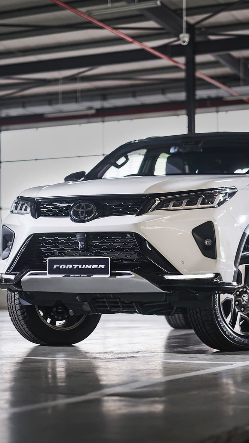 White Toyota Fortuner SUV with glowing LED headlights and a silver grille parked inside a dark modern garage.
