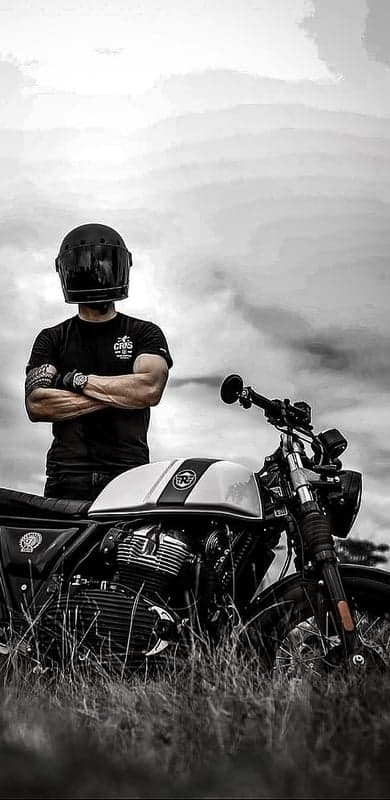 Motorcyclist with helmet poses by classic motorcycle in B&W