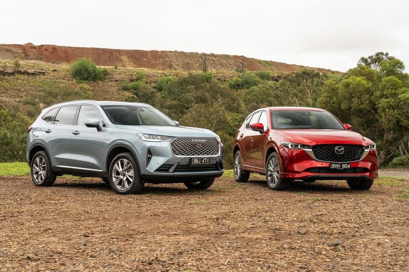 Haval H6 and Mazda CX-5 SUVs parked on a gravel hill under a cloudy sky in a landscape view.