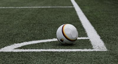 Soccer ball on a green field near white corner lines