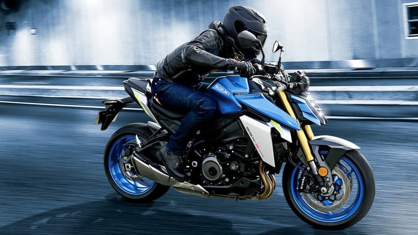 Suzuki GSX-S1000 motorcycle in blue and silver speeding with motion blur against a concrete tunnel backdrop.