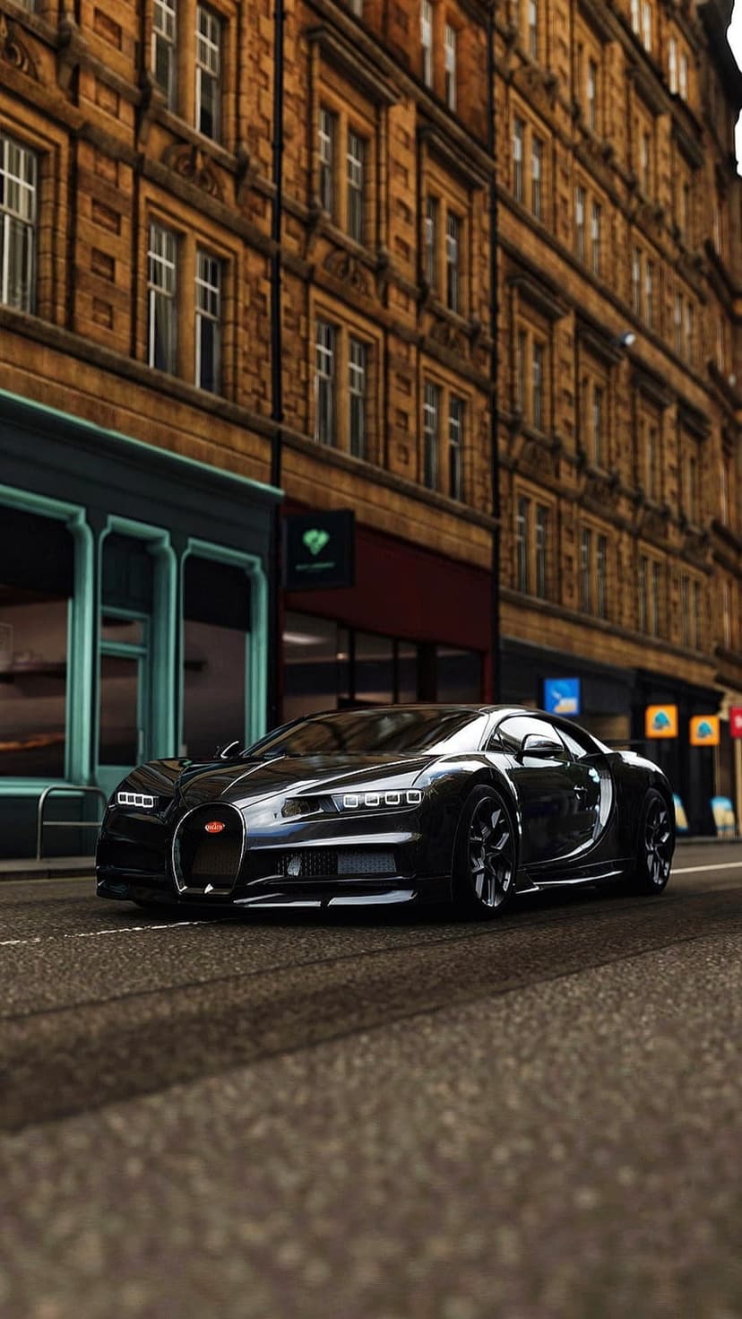 Black Bugatti Chiron cruises a brick-lined city street featuring historic architecture and urban storefronts.