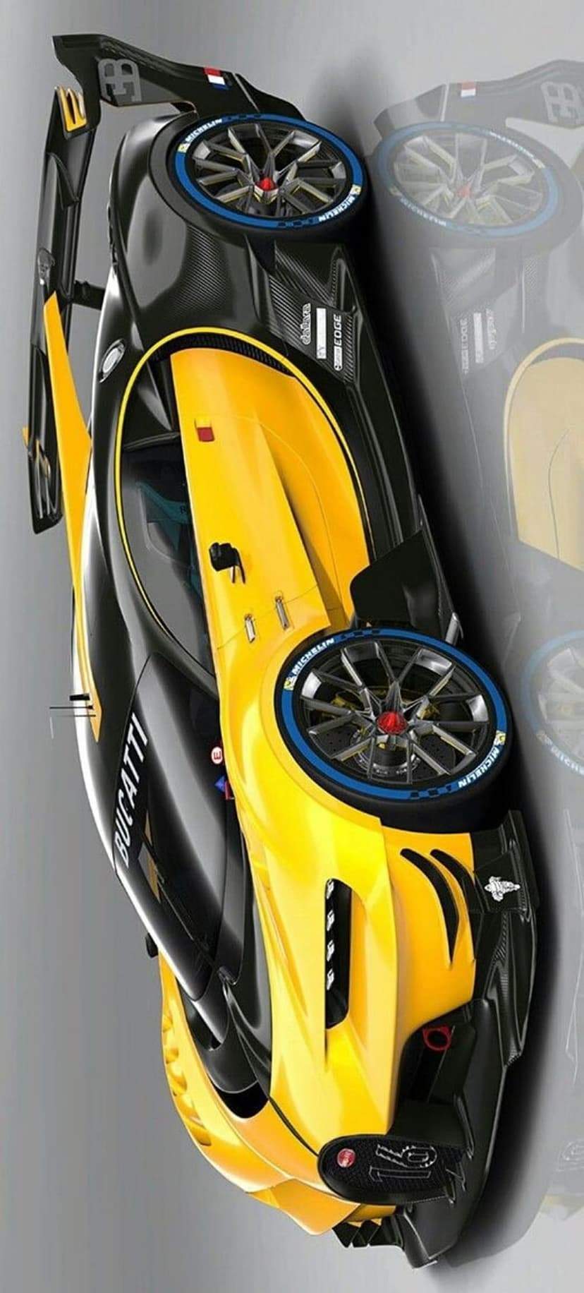 Yellow Bugatti Chiron race car viewed from a high angle showing carbon fiber parts and Michelin tires on asphalt.
