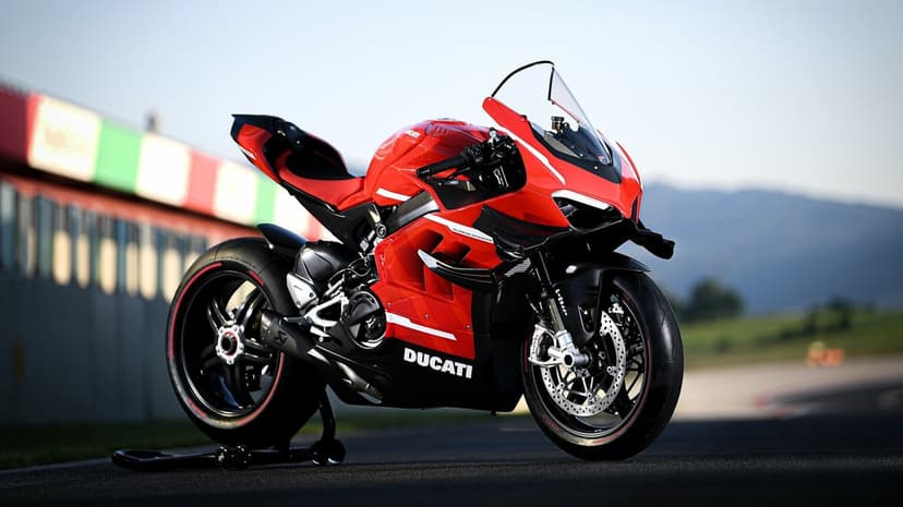 Red Ducati Superleggera V4 sportbike on a track with carbon fiber details and blurred pit lane background.