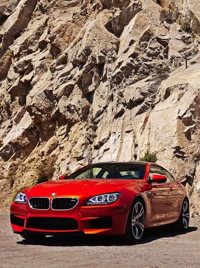 Red BMW M6 Performance Car Rocky Terrain Mobile Background