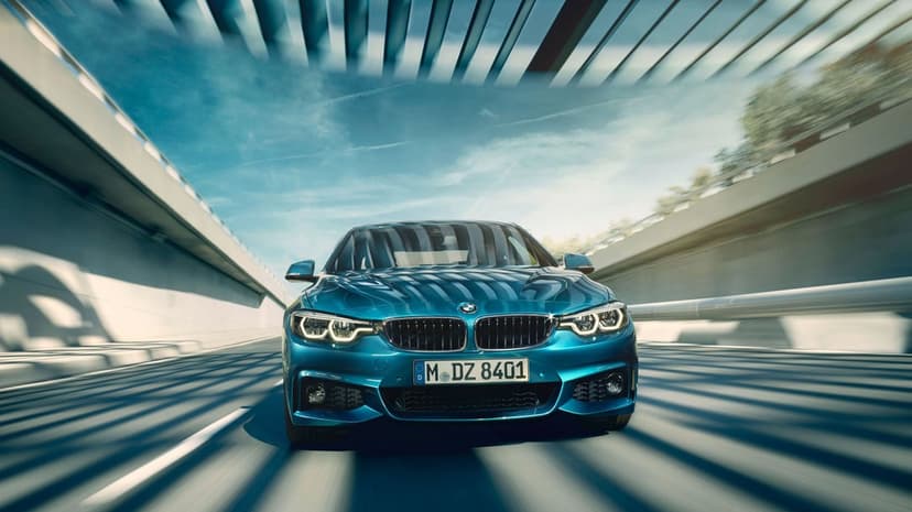 Blue BMW sports sedan driving through a modern tunnel with motion blur and overhead architectural lighting.