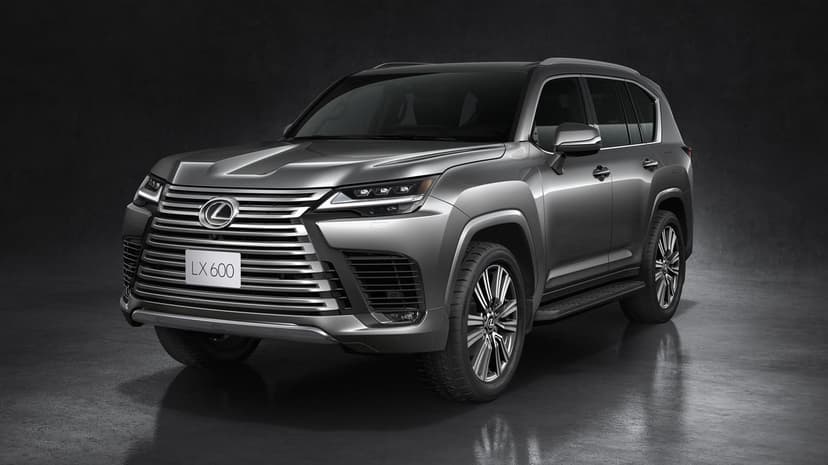 Silver Lexus LX 600 luxury SUV with chrome spindle grille and multi-spoke wheels in a dark studio environment.