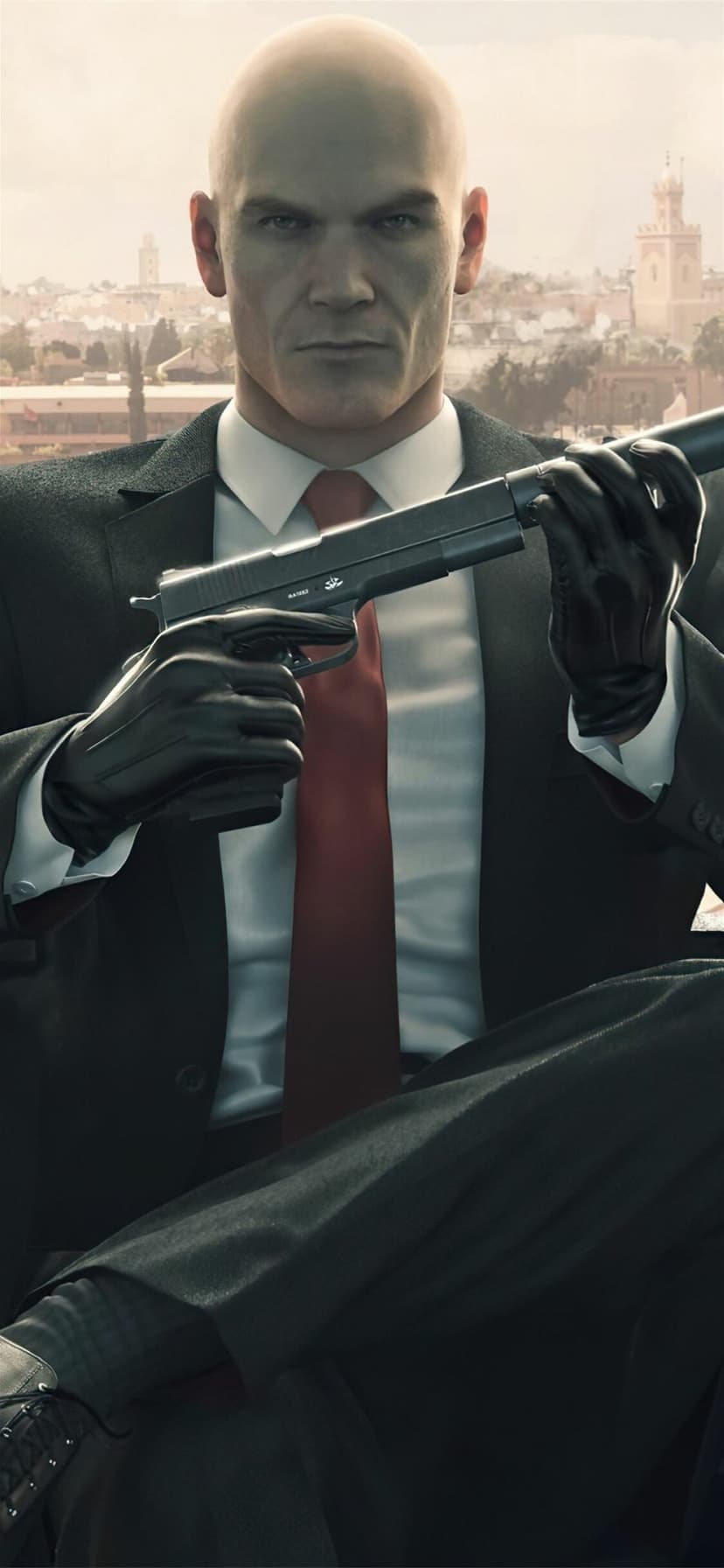 Agent 47 in a black suit and red tie holding a suppressed pistol against a blurred city background.