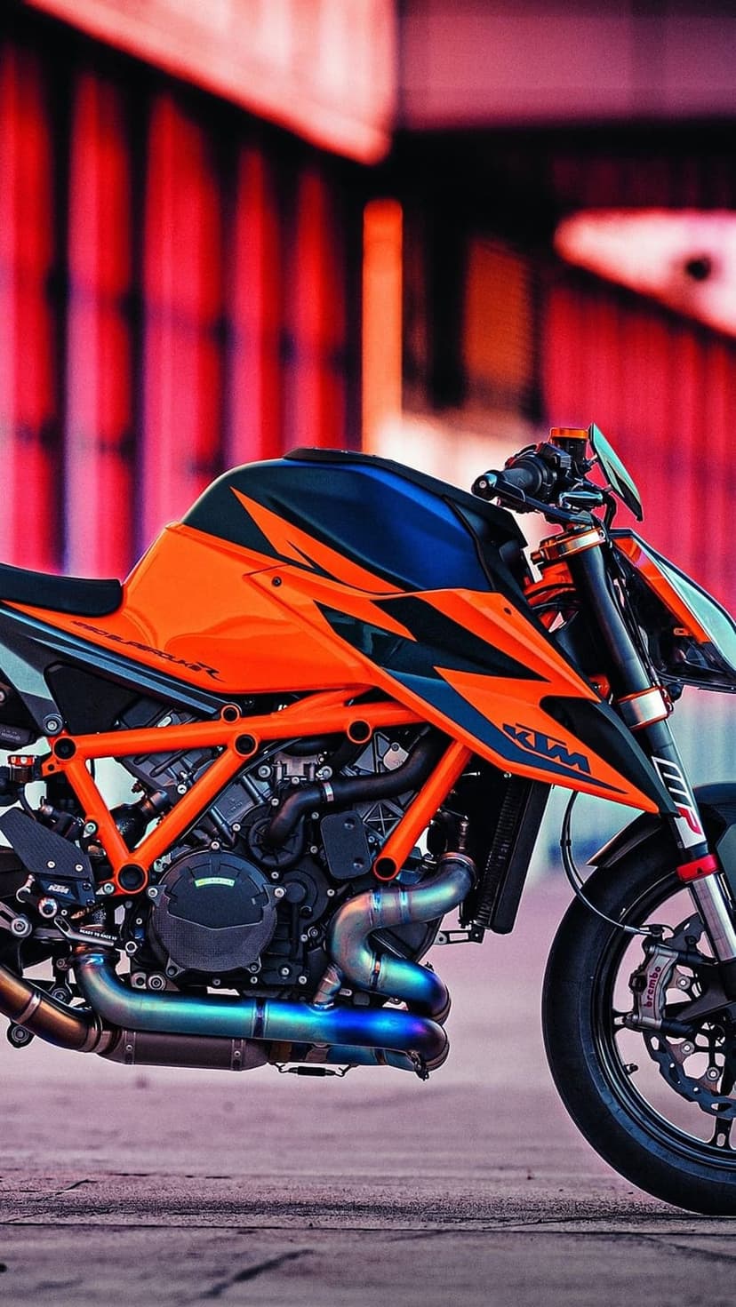 KTM superbike featuring an orange trellis frame and blue accents parked on a textured concrete surface.