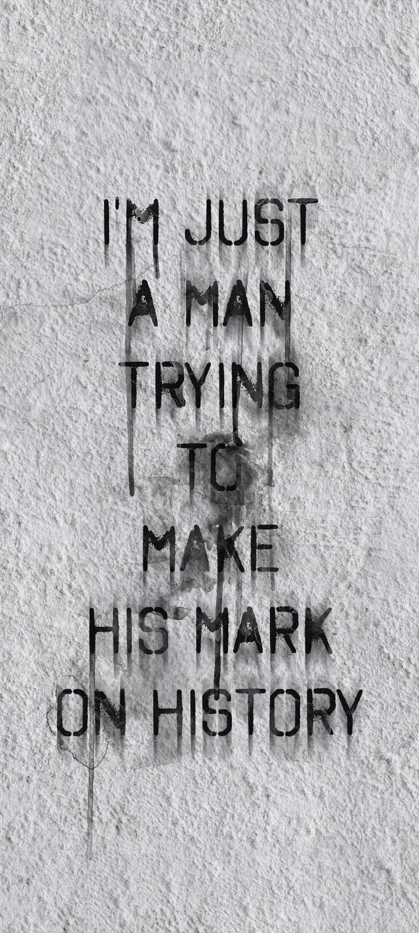 Black stencil text with dripping paint on a white textured wall states I'm just a man trying to make his mark.