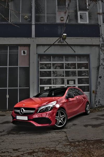Red Mercedes A-Class parked in front of industrial garage