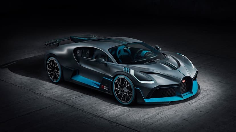 Bugatti Divo supercar in matte gray with cyan highlights parked on a textured concrete floor in a dark studio.