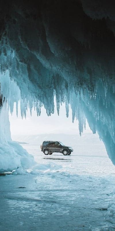 Car driving on frozen lake amidst ice cave