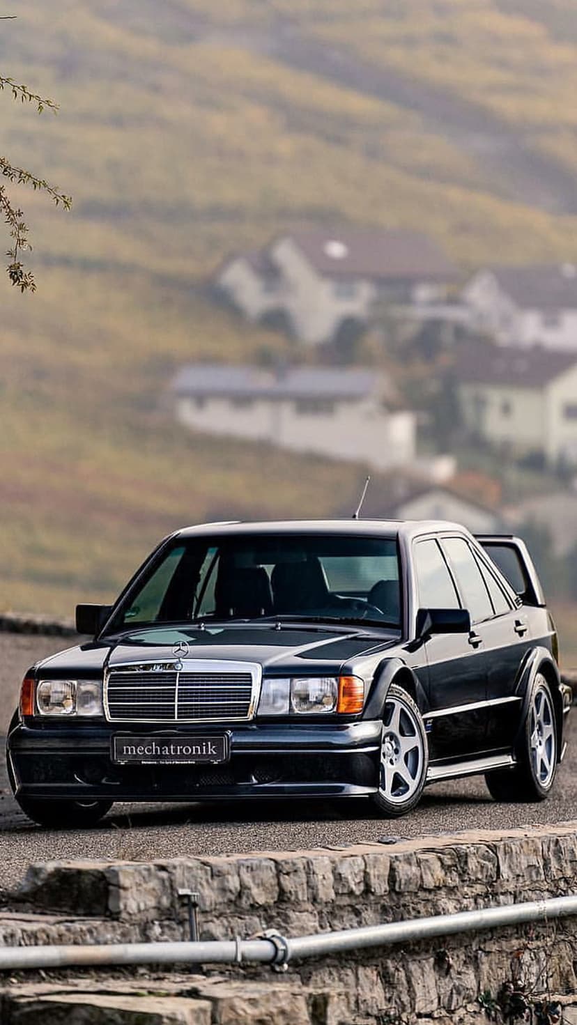 Black Mercedes-Benz 190E Evolution II sports sedan featuring a large rear wing and flared wheel arches outdoors.