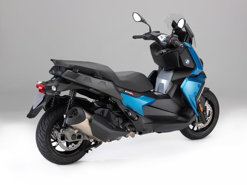 Blue and black BMW C 400 X urban scooter parked in a studio with grey background and soft overhead lighting.