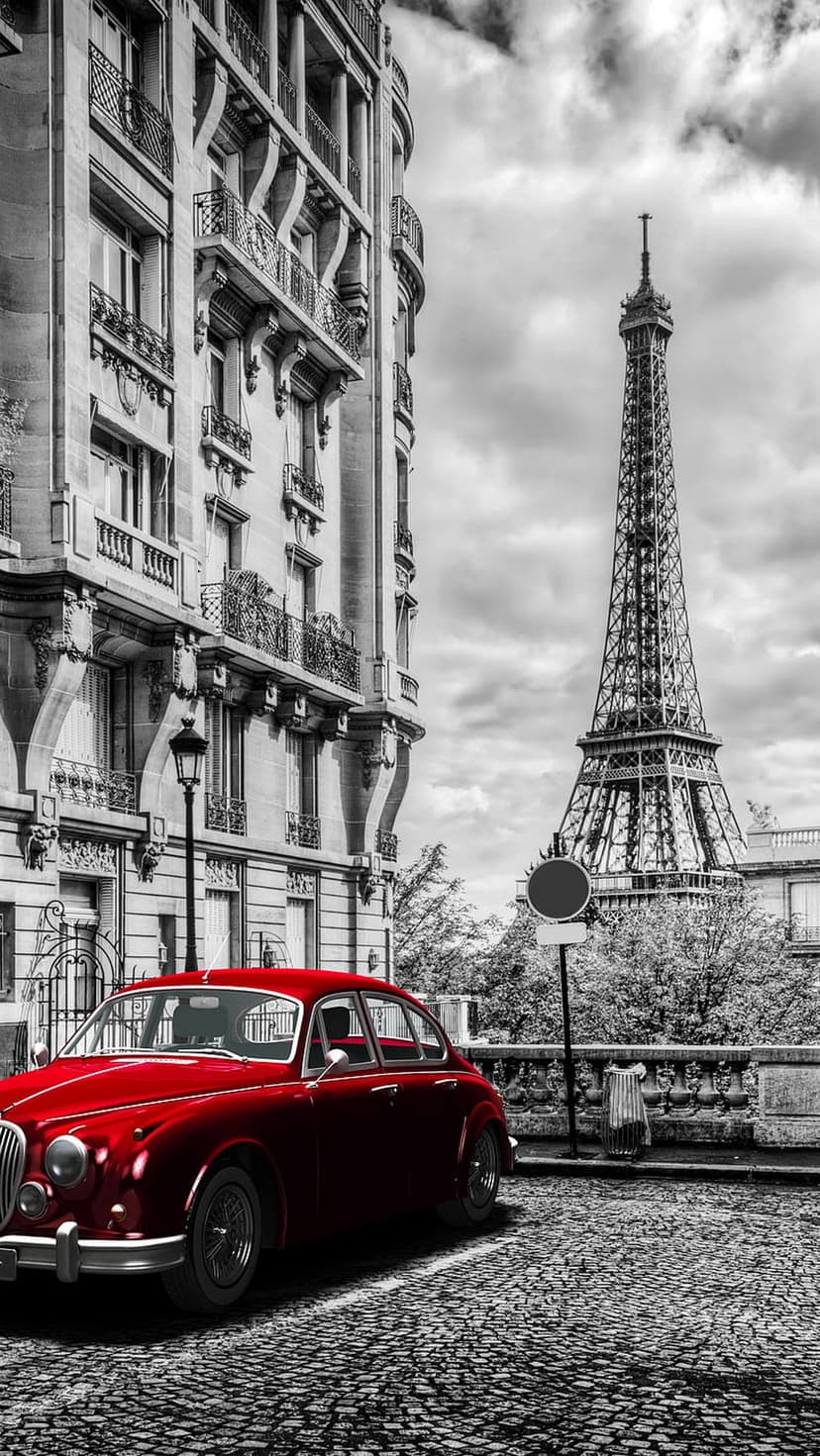 Vintage red car parked on a cobblestone Paris street with the Eiffel Tower standing in the background.