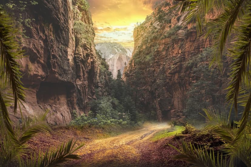 Dusty trail between steep rocky cliffs and palm trees under a hazy golden sunset in a tropical jungle canyon.