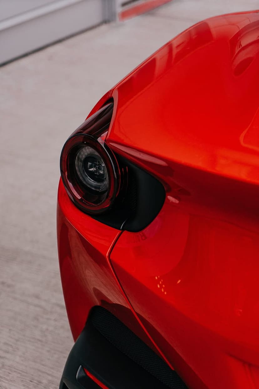 Circular LED taillight of a red sports car with glossy reflections and sharp aerodynamic body lines.