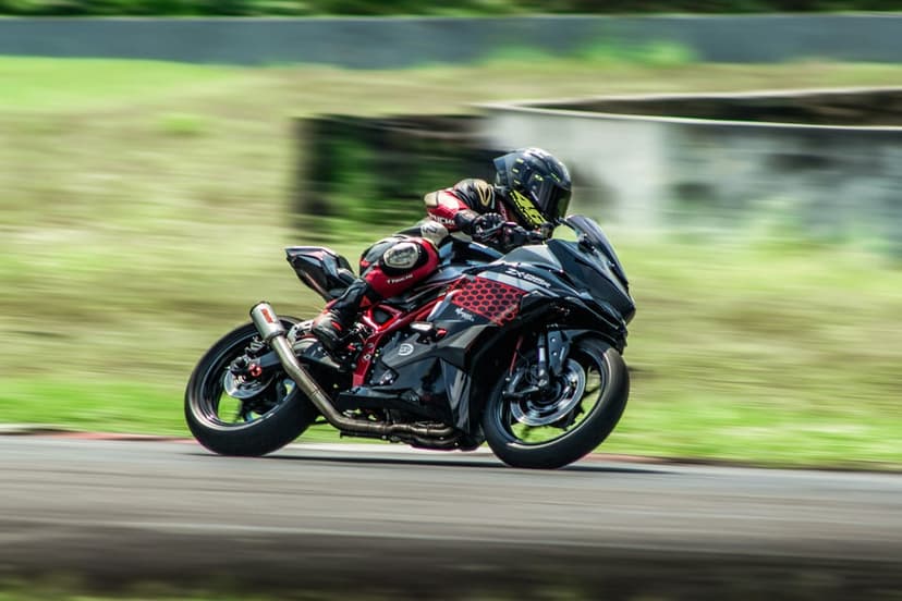 Motorcyclist in racing leathers leans a red and black sport bike into a sharp curve on a blurred asphalt track.