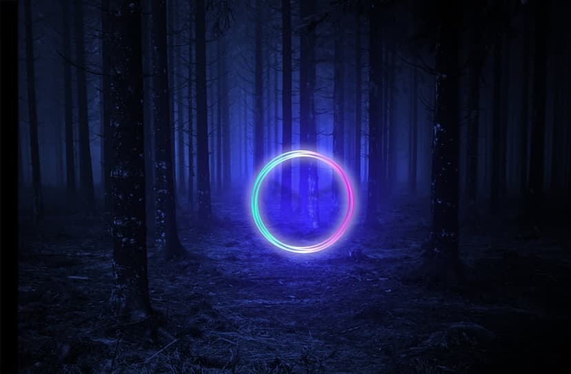A glowing blue and pink ring hovers between tall trees in a dark, foggy forest at night, casting light on grass.