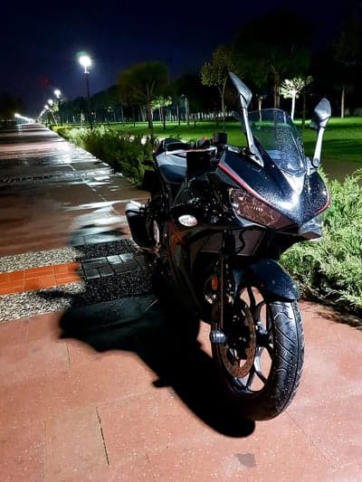 Black motorcycle parked on wet path at night