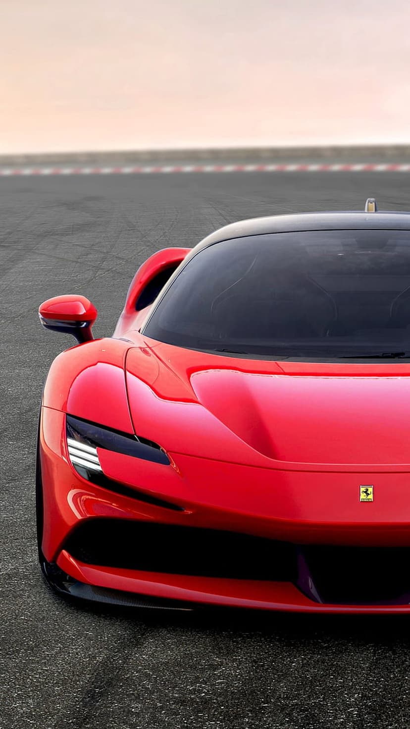 Red Ferrari SF90 Stradale front view with LED headlights and prancing horse emblem on a blurred racetrack.