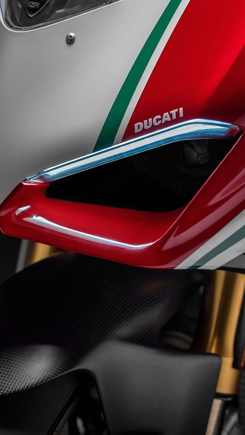 Red Ducati motorcycle fairing with Italian flag stripes, carbon fiber accents, and gold suspension components.