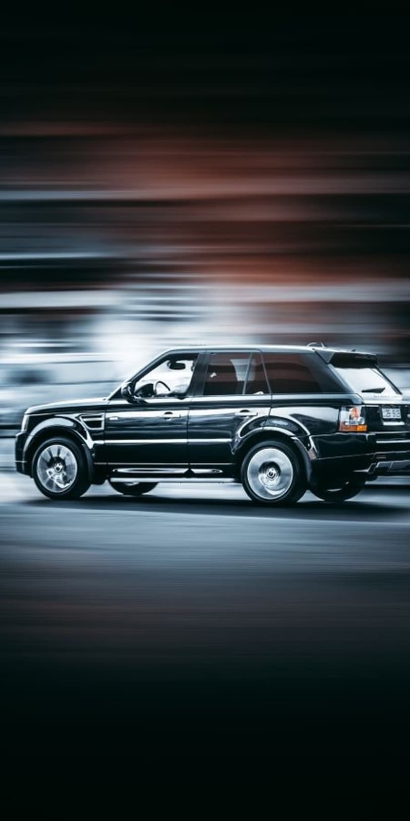 Black Range Rover Sport driving fast on a night road with colorful light streaks and a cinematic motion blur effect.