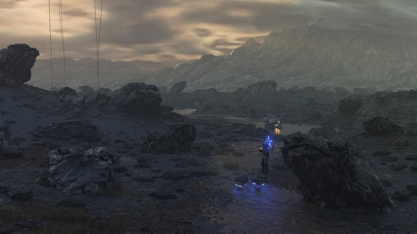 Lone porter in a blue-lit suit stands amidst dark jagged rocks and misty mountains under a golden sky.