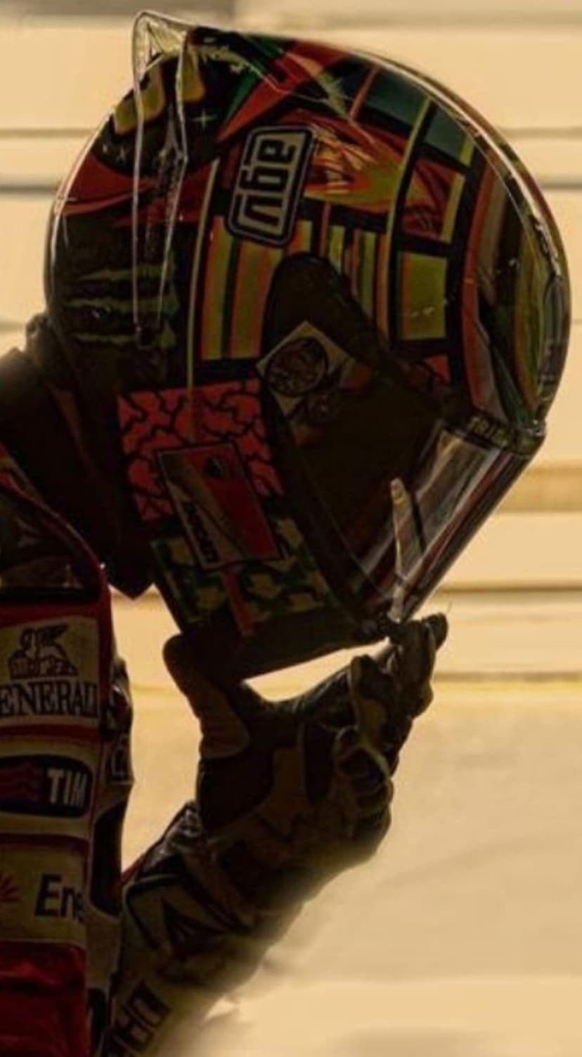 Valentino Rossi's AGV helmet with sun and moon graphics as a gloved hand touches the visor in a close-up profile.