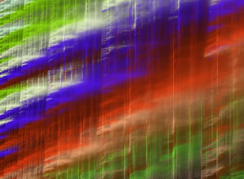 Vertical streaks of emerald green, deep blue, and ruby red light radiate with blurred motion and energy.