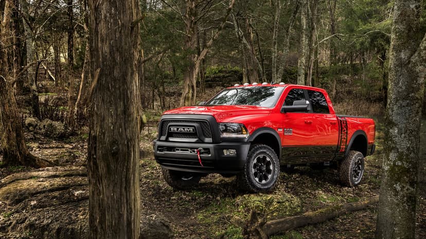 Red Ram 2500 Power Wagon truck with off-road tires and a winch parked on a mossy, rocky forest trail.