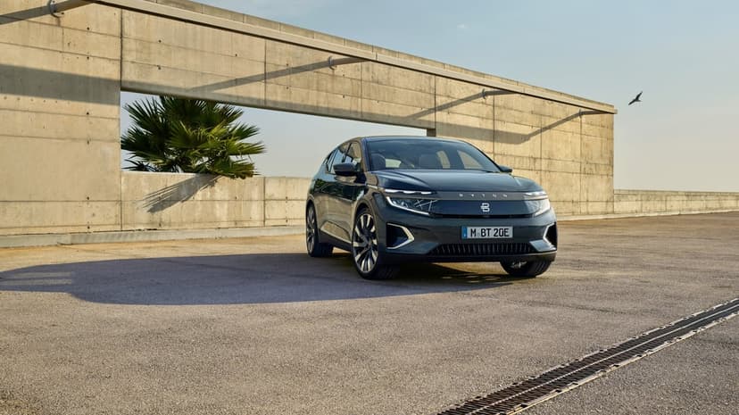 Byton M-Byte electric SUV on a concrete rooftop with a minimalist wall, palm tree, and clear blue sky.
