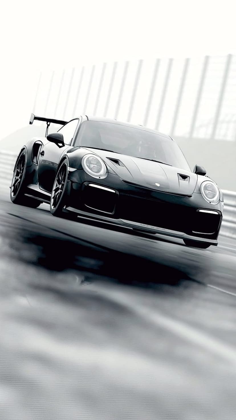 Porsche 911 GT2 RS racing on a wet asphalt track with water splashing behind the large rear wing in monochrome.
