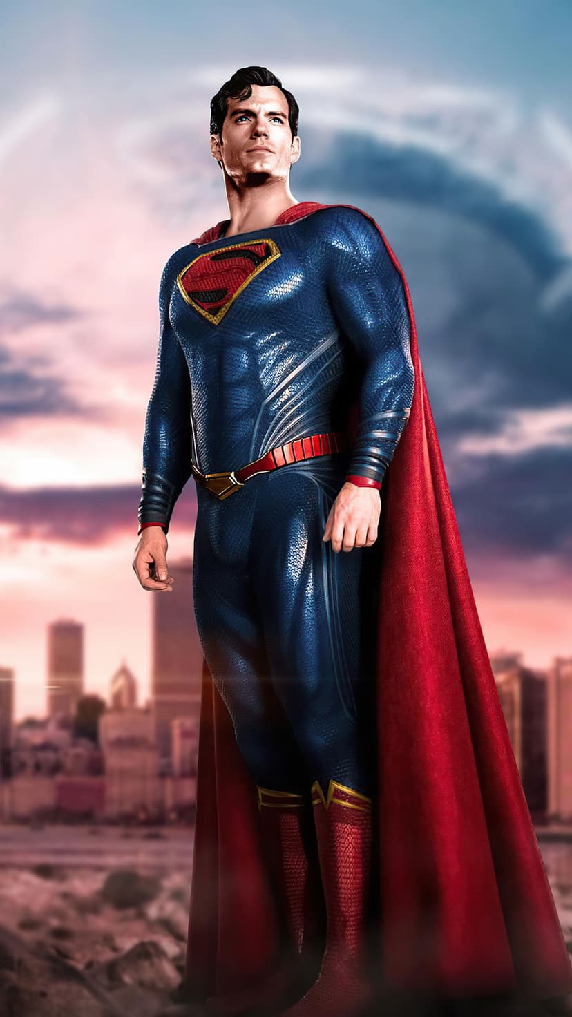 Superman stands in a full blue suit and red cape against a dramatic sunset city skyline with glowing clouds.