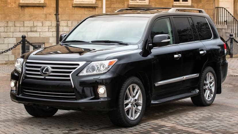 Black Lexus LX 570 SUV parked on a cobblestone path in front of a tan stone building in daylight.