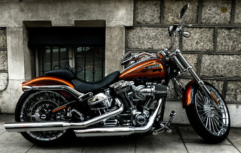 Orange Harley Davidson motorcycle with polished chrome accents parked on a sidewalk against a textured stone wall.