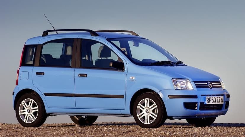 Light blue Fiat Panda hatchback with black trim and roof rails parked on a gravel surface under a clear sky.
