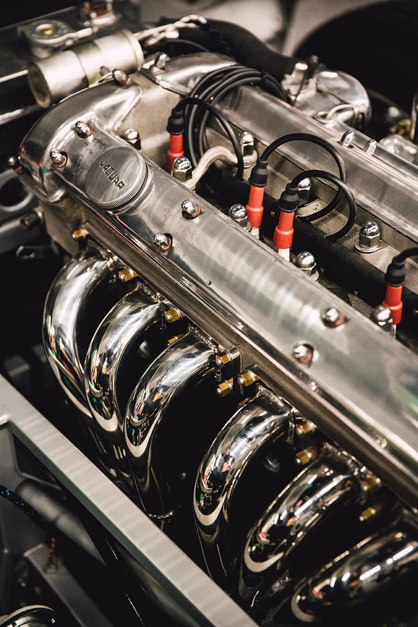 Jaguar engine block features polished chrome surfaces, red spark plug wires, and a circular manufacturer emblem.