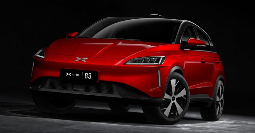Red XPeng G3 electric SUV with glowing headlights and silver wheels parked in a dark studio setting.