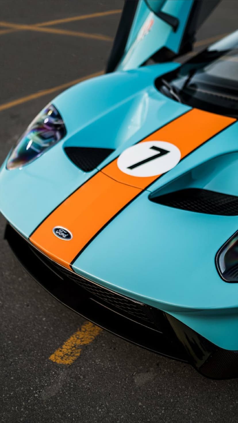 Ford GT racing car with open doors featuring a blue and orange Gulf livery with a prominent number seven decal.