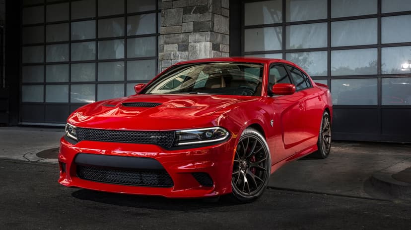 Red Dodge Charger SRT Hellcat parked in front of a glass-windowed garage with bronze performance wheels.