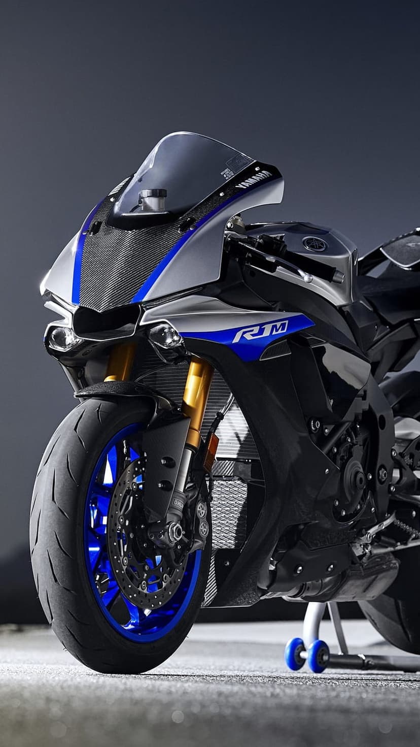 Yamaha R1M superbike front fairing with carbon fiber texture and vibrant blue wheel accents in a close-up view.