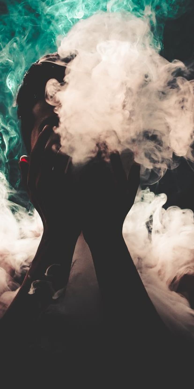Silhouetted figure with raised hands surrounded by swirling clouds of teal, peach, and white glowing smoke.