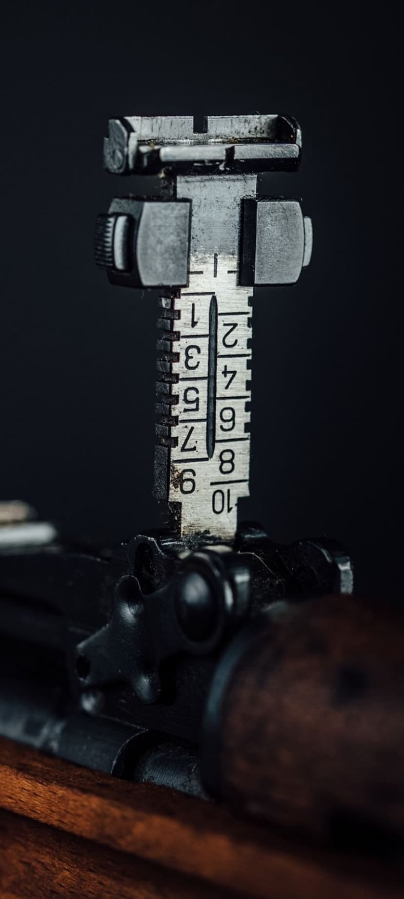 Steel rifle rear sight with engraved numbers one through ten against a dark, out-of-focus background.
